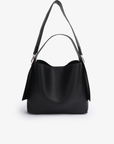 Remi and Reid Paloma Shoulder Bag in textured black vegan leather, featuring a unique wing-like silhouette with a flat top handle and a removable, adjustable shoulder strap.