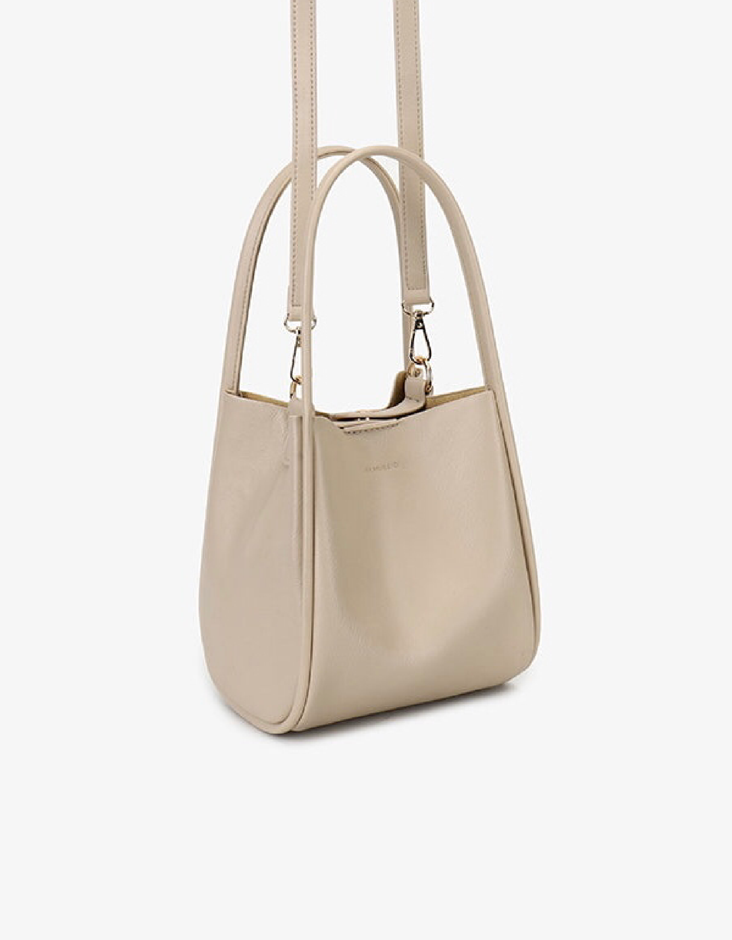 Cream-colored mini tote attached in a buckled detachable, adjustable strap by Remi and Reid.