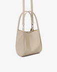 Cream-colored mini tote attached in a buckled detachable, adjustable strap by Remi and Reid.