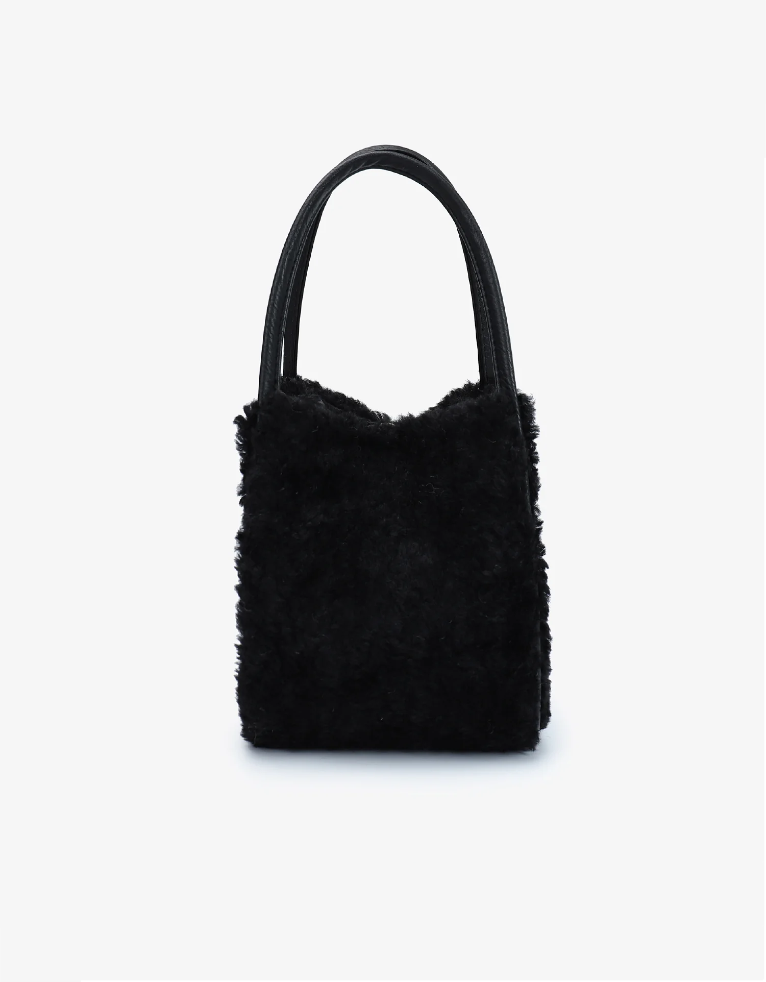 A black mini tote bag with shearling texture and two handles by Remi and Reid.