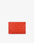 A large orange woven leather clutch with a structured shape and light gold hardware by Remi and Reid.