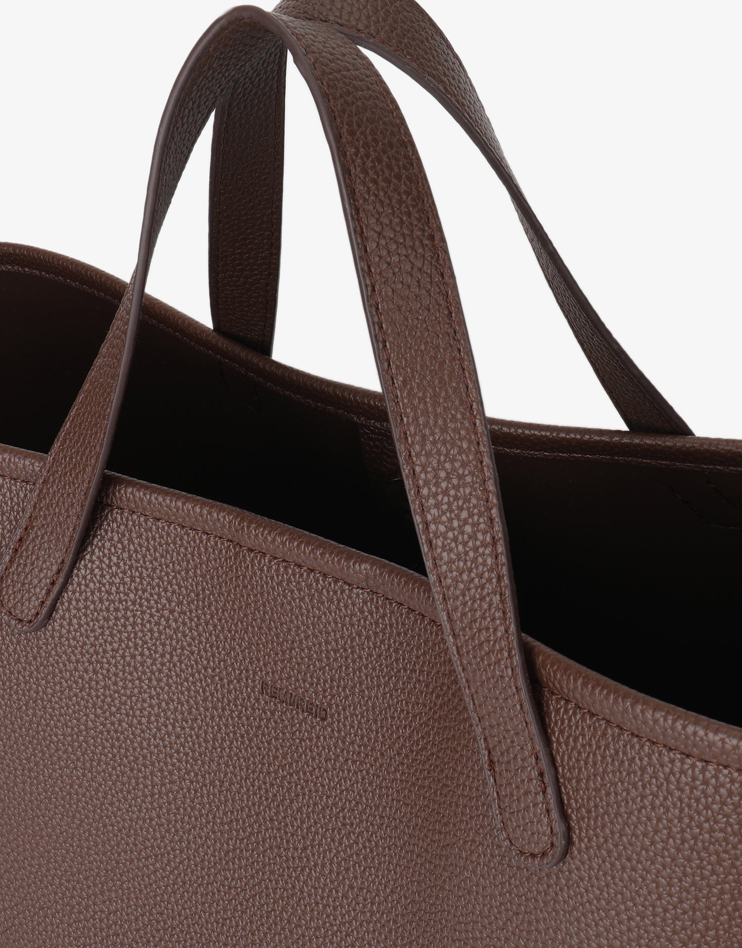 Detailed view of the dark brown textured finish and stitched handles of the Nala Tote by Remi and Reid.