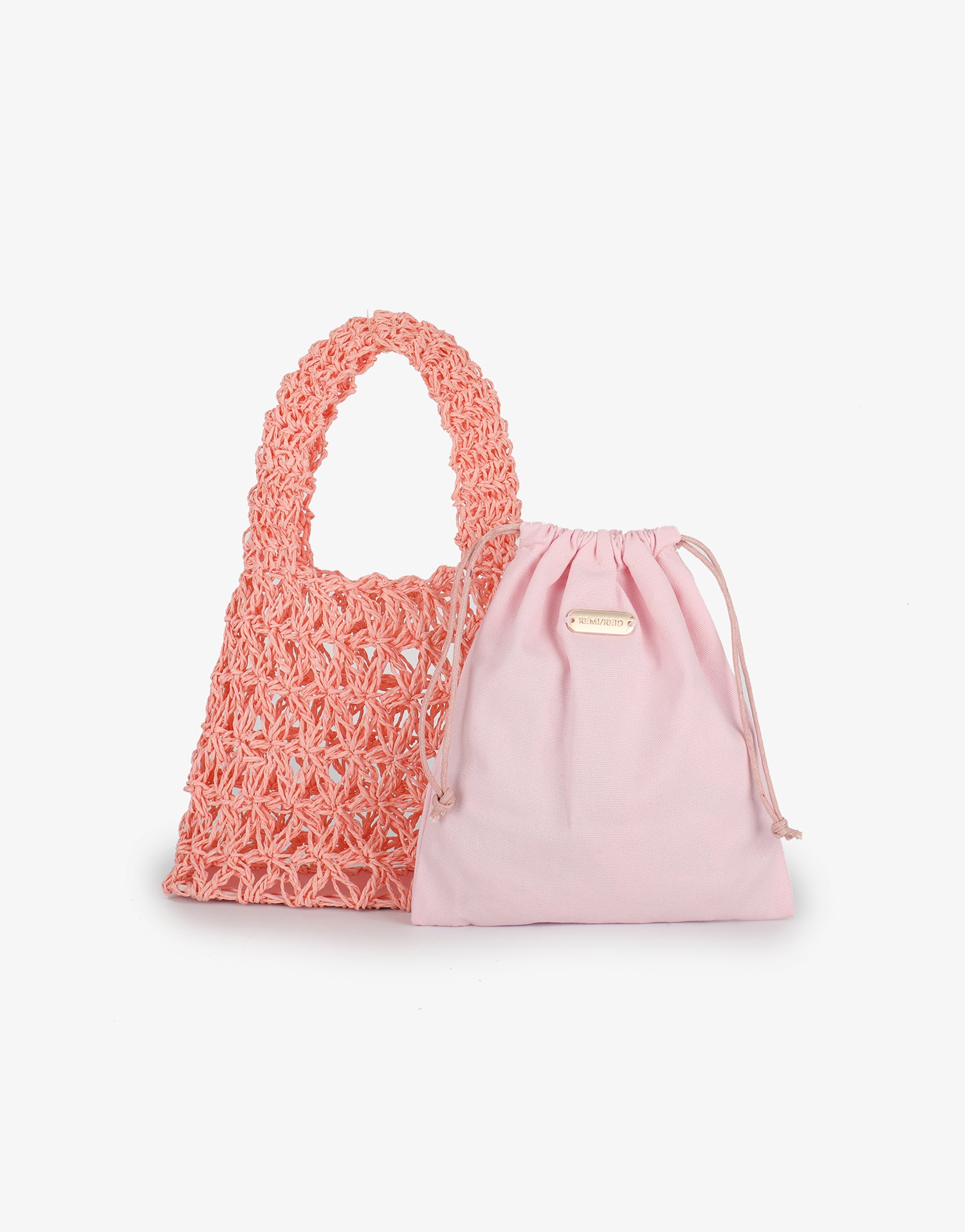Front view of the open-weave crochet Nigella Woven Pink by Remi and Reid with its matching pink drawstring pouch placed beside it.
