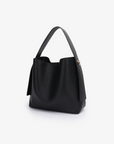 Remi and Reid Paloma Shoulder Bag in textured black vegan leather, featuring a unique wing-like silhouette with a flat top handle and a removable, adjustable shoulder strap.
