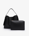 Remi and Reid Paloma Shoulder Bag in textured black vegan leather, featuring a unique wing-like silhouette with a flat top handle wit matching black pouch.