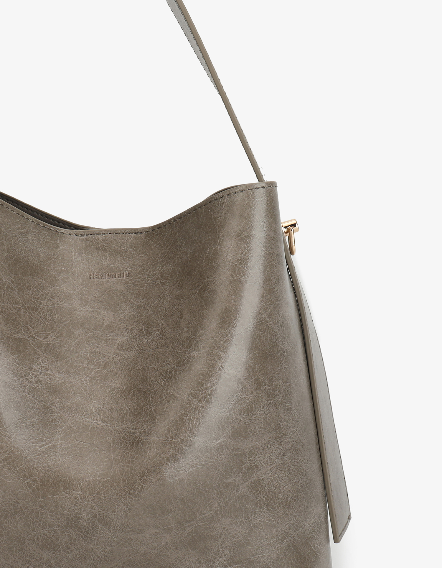 Close-up of Paloma Waxed vegan leather shoulder bag in gray featuring a wide single strap handle and gold-tone buckle hardware on the side.
